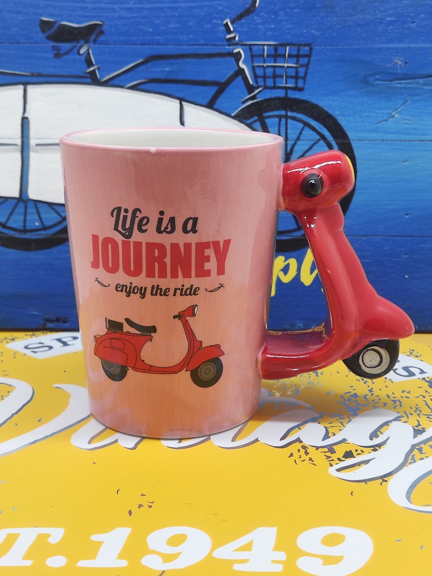 Caneca rosa com alça em forma de scooter vermelha e texto motivacional