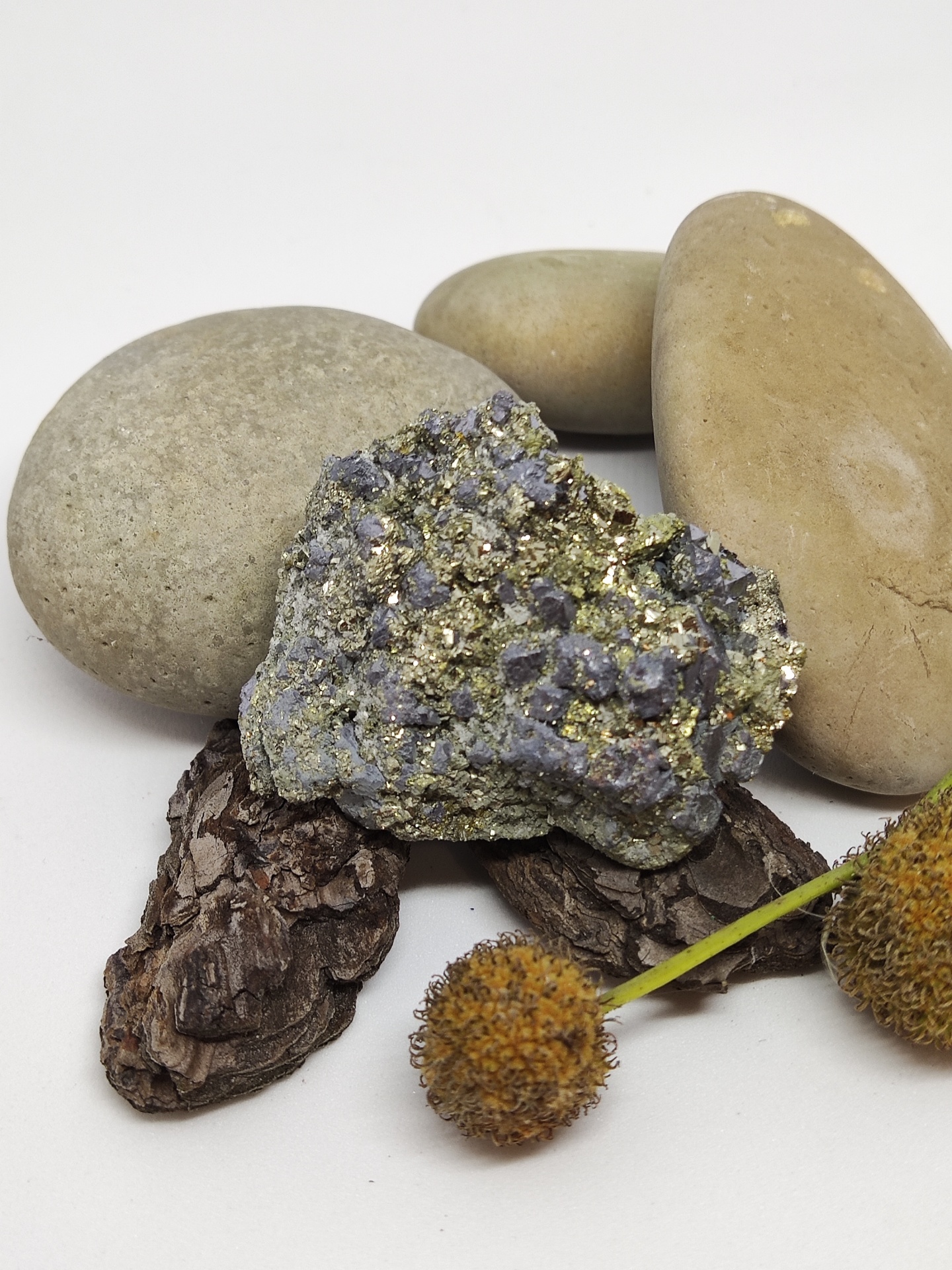 Pedra mineral com cristais dourados e púrpuras junto a pedras e elementos naturais