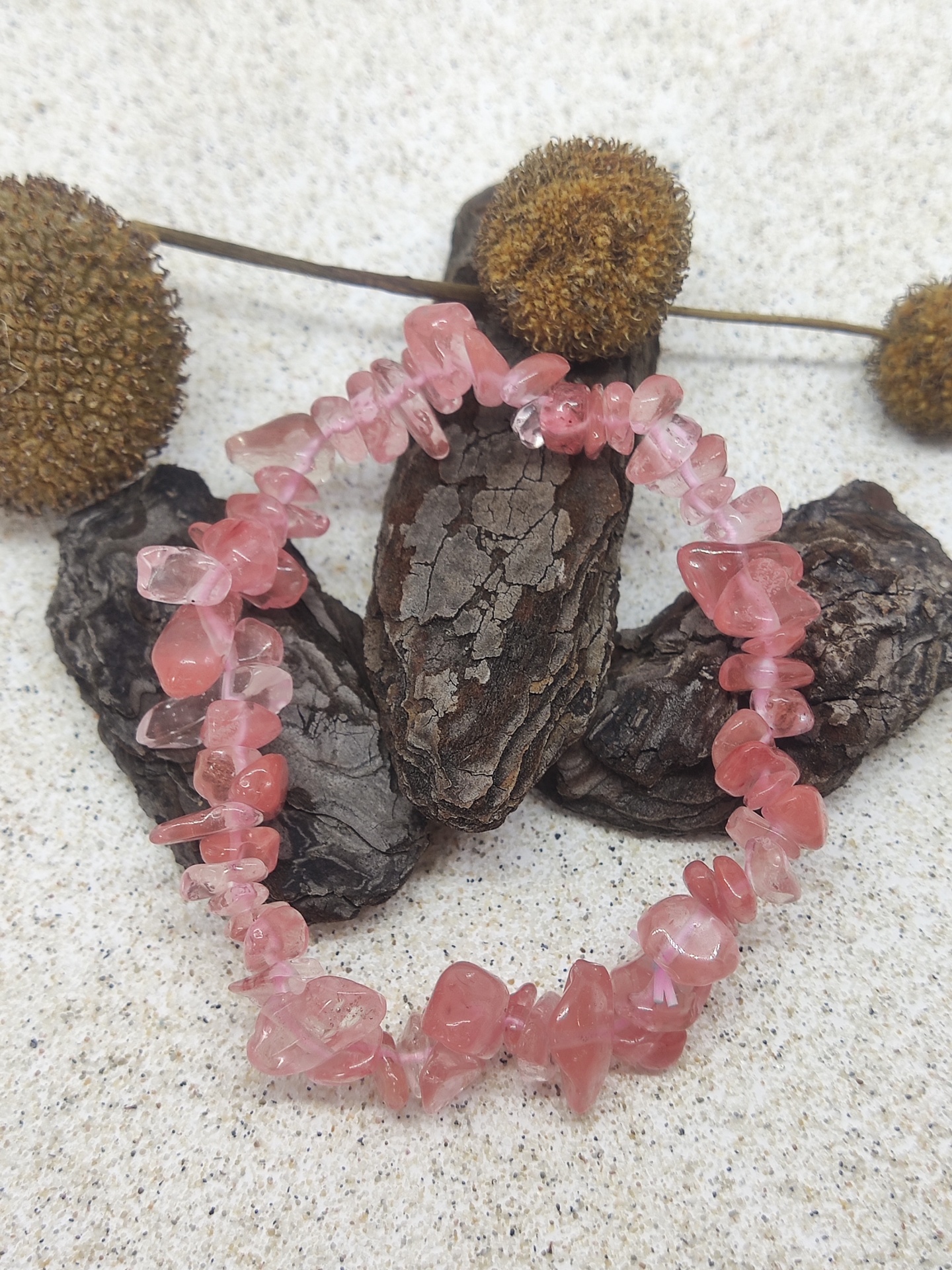 Pulseira de pedras naturais rosa sobre casca e flores secas