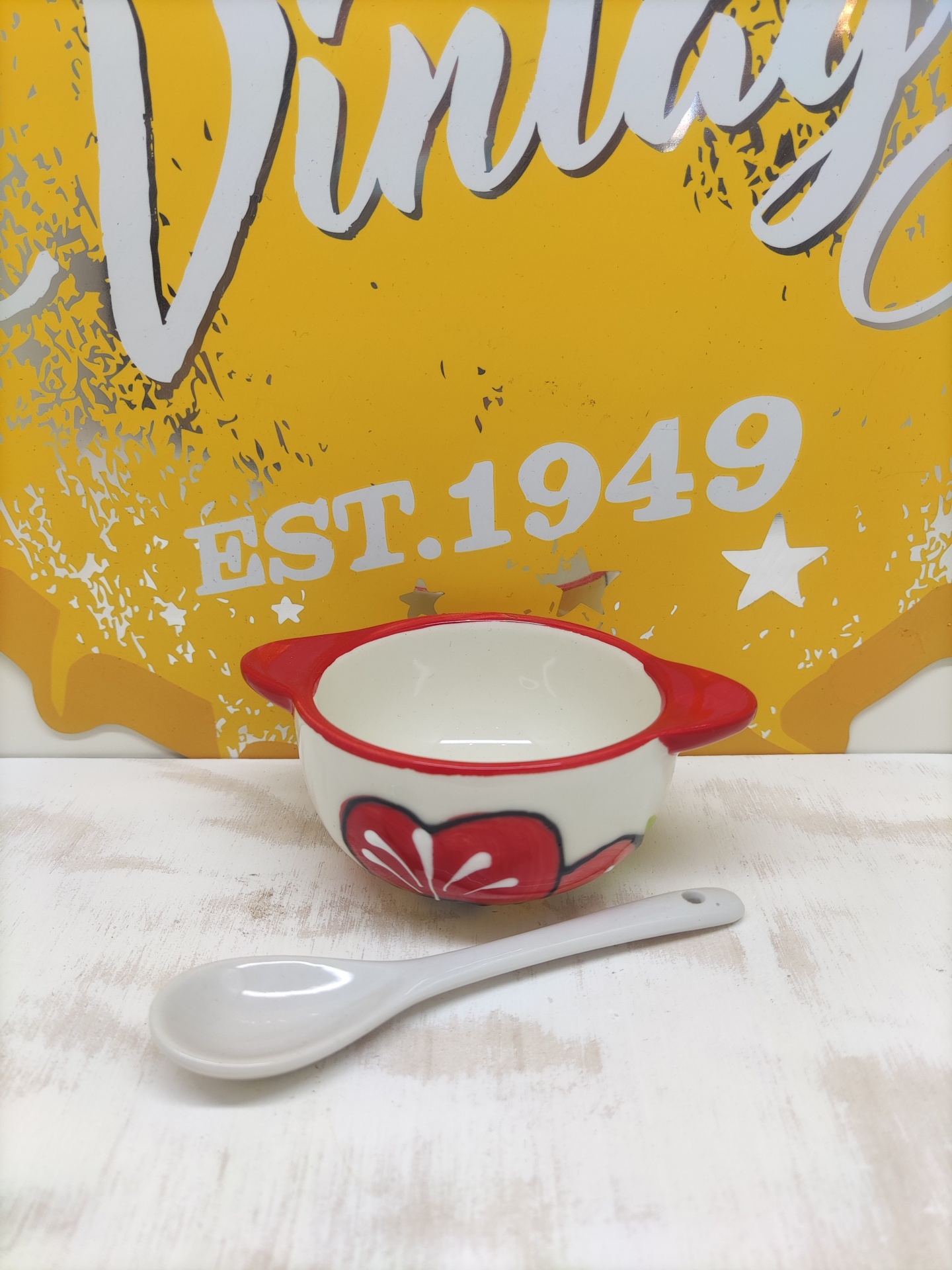 Mini taça vermelha e branca em cerâmica com colher e fundo amarelo com texto vintage