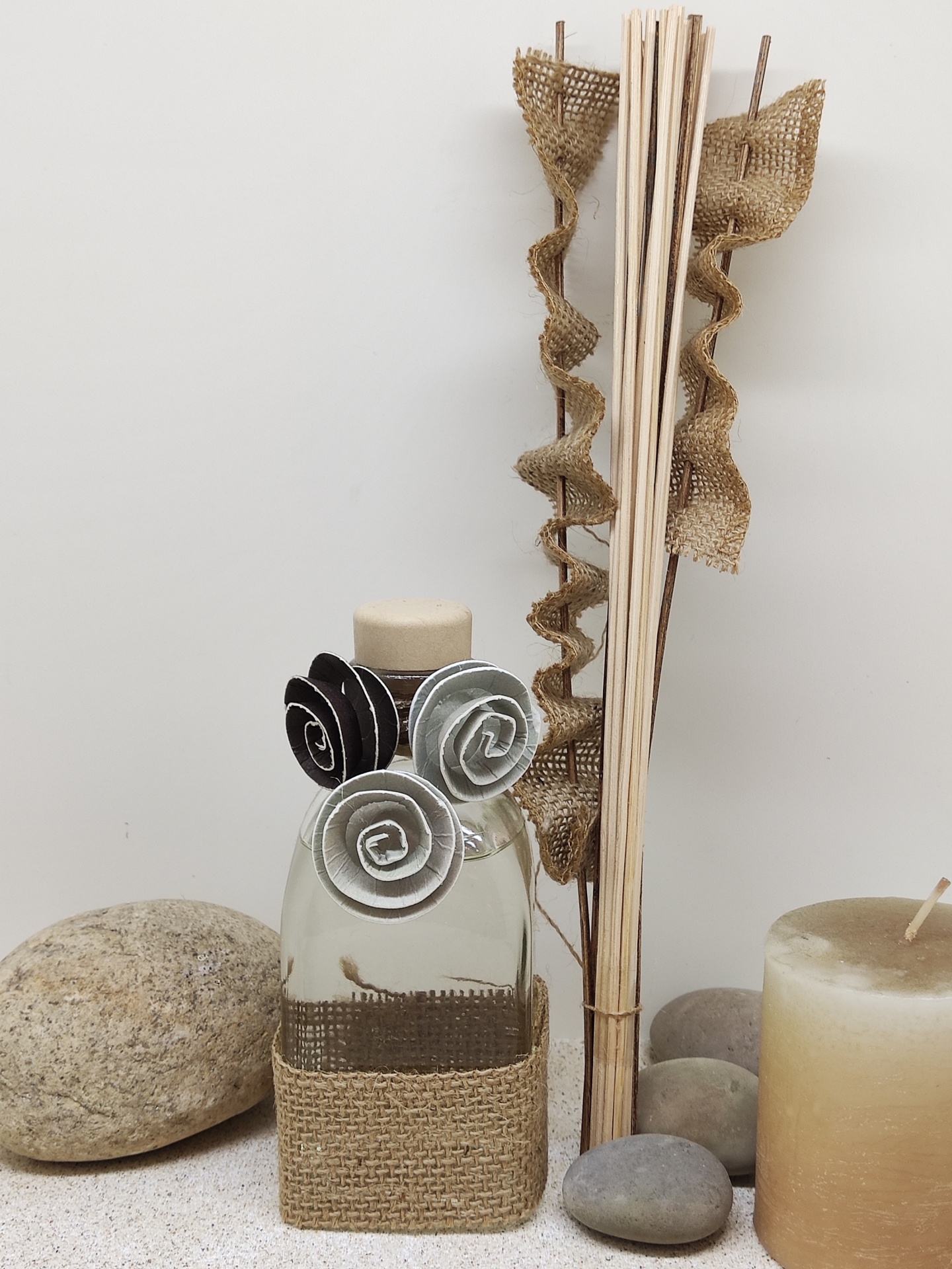 Frasco decorativo em vidro com flores de tecido, pedras, velas e hastes de madeira com fitas rústicas