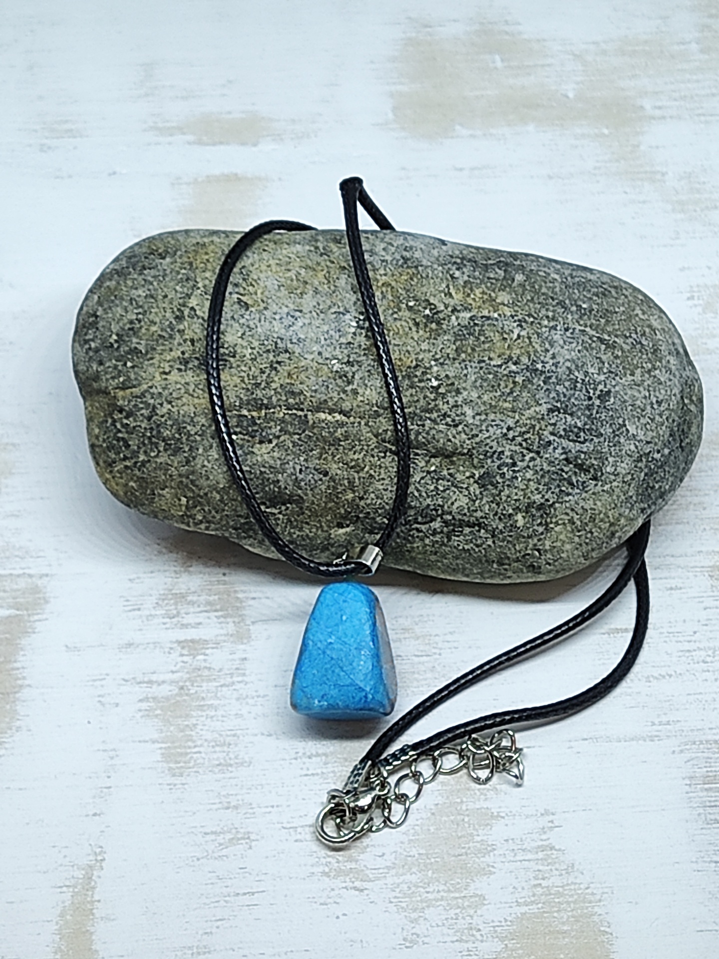 Colar com pendente azul de pedra polida sobre pedra cinzenta