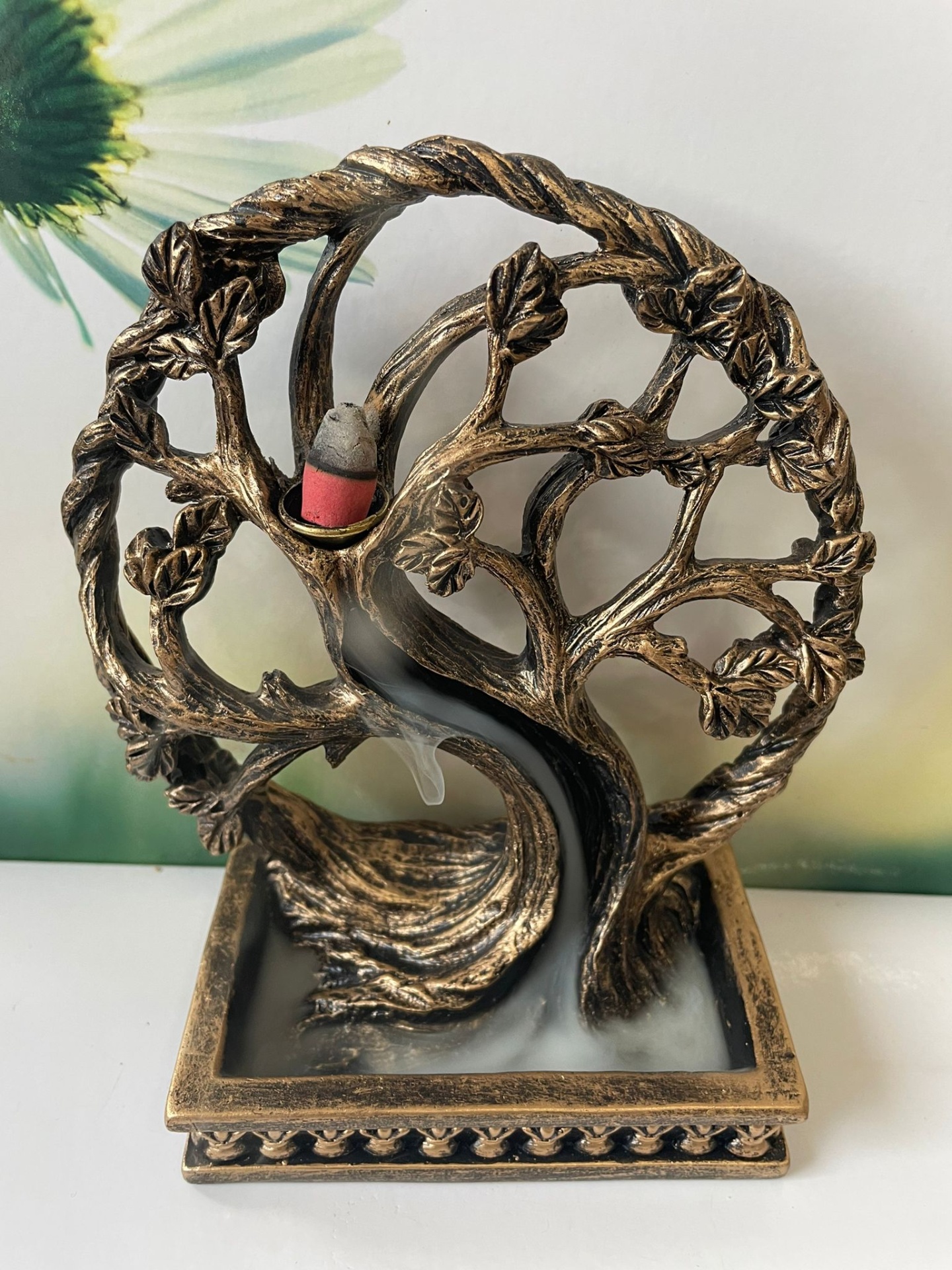 Incensário em formato de árvore dourada com cone de incenso vermelho e fumo descendo