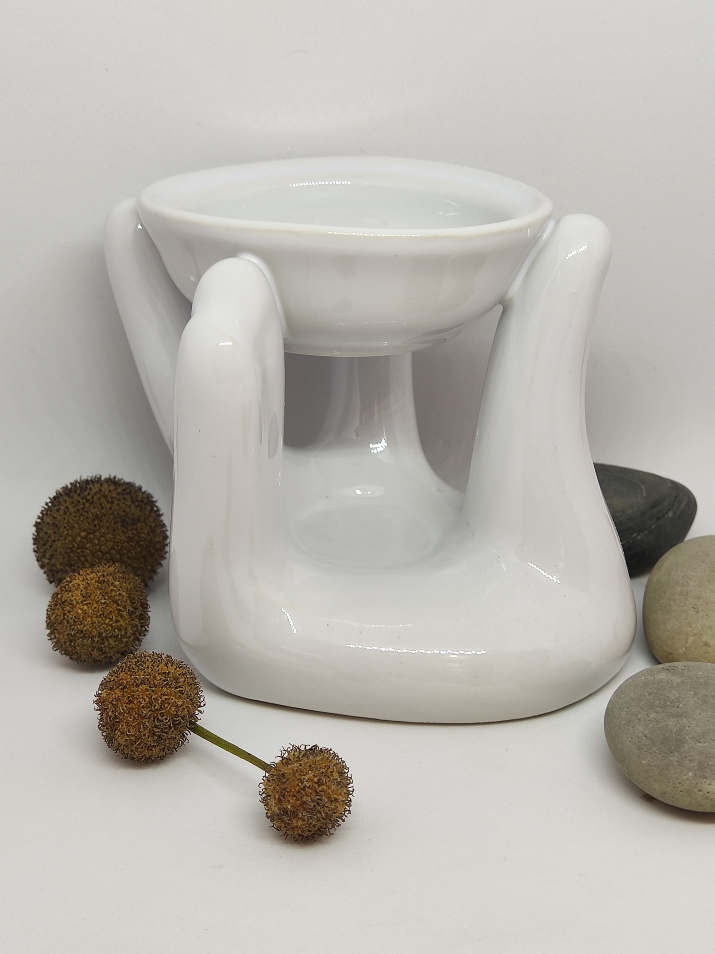 Suporte decorativo branco em cerâmica com tigela e pedras ao lado