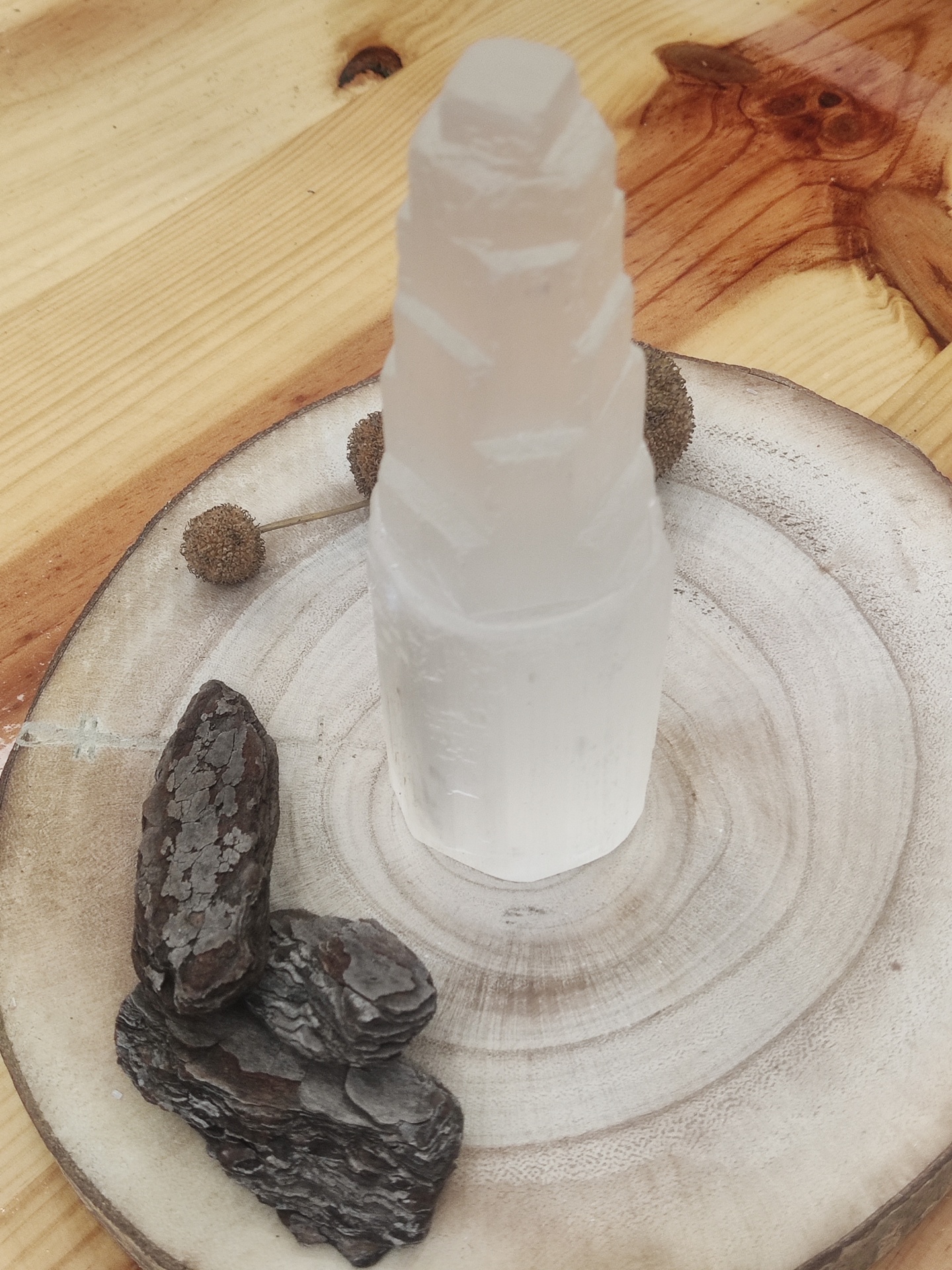 Torre de cristal branco translúcido sobre base de madeira clara e cascas escuras