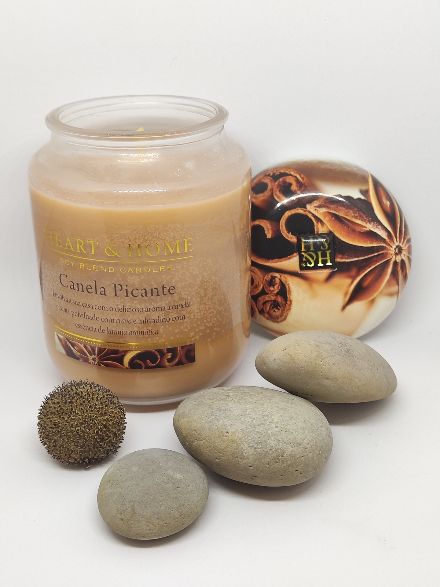Vela perfumada Canela Picante com pedras e semente num fundo branco