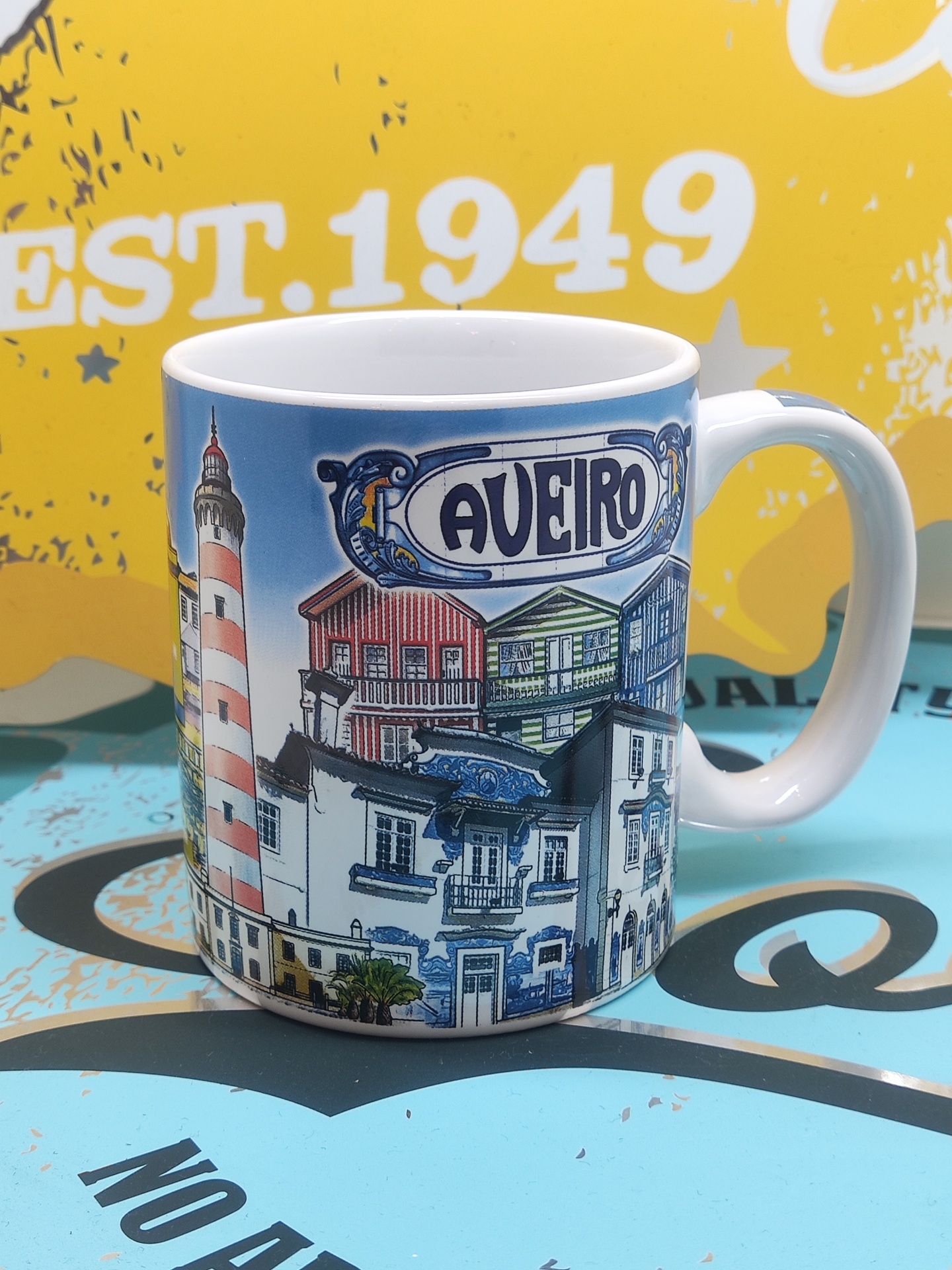Caneca branca com ilustração colorida de Aveiro e texto 'AVEIRO'.