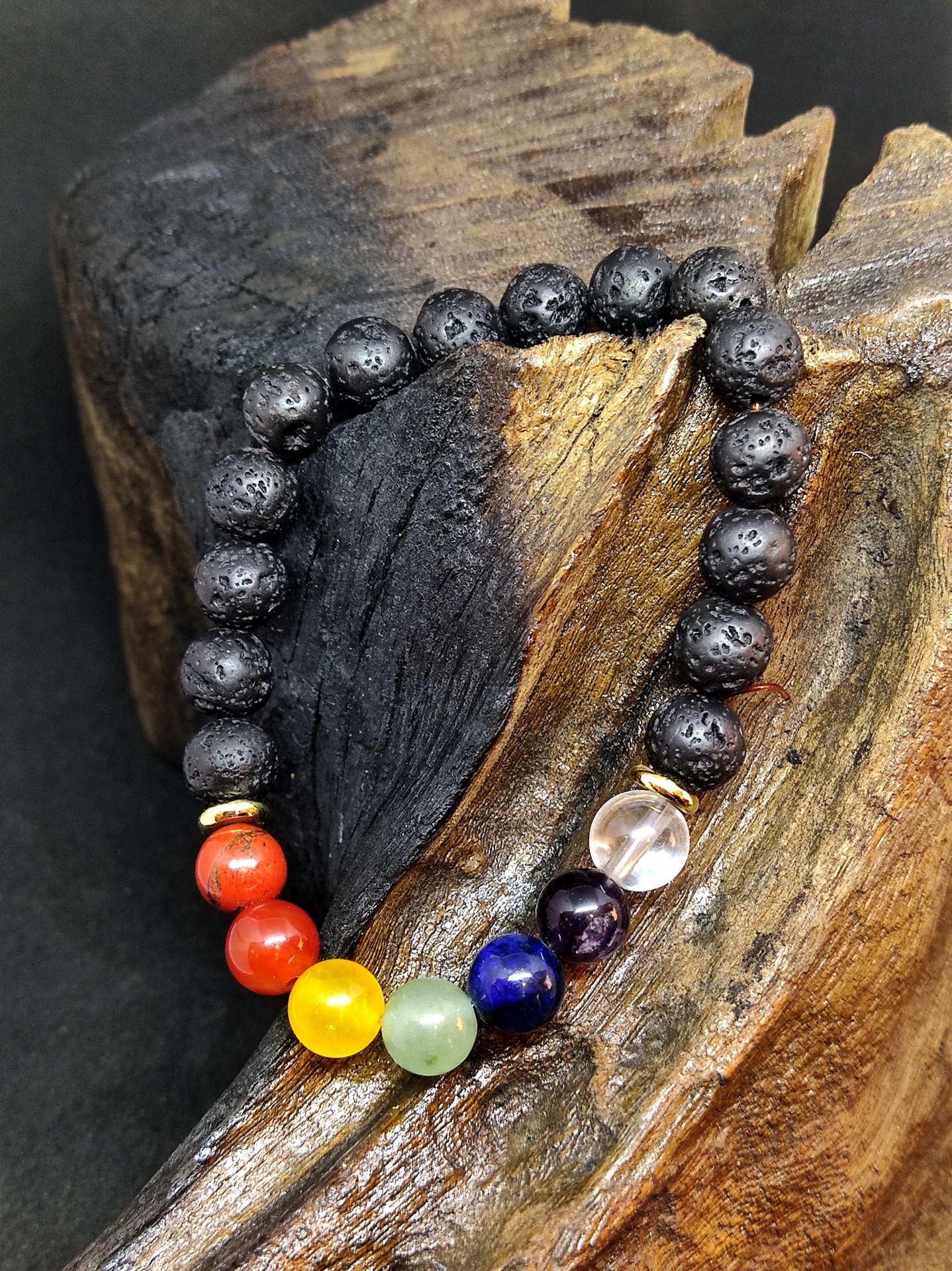 Pulseira de pedras coloridas e vulcânicas sobre madeira escura