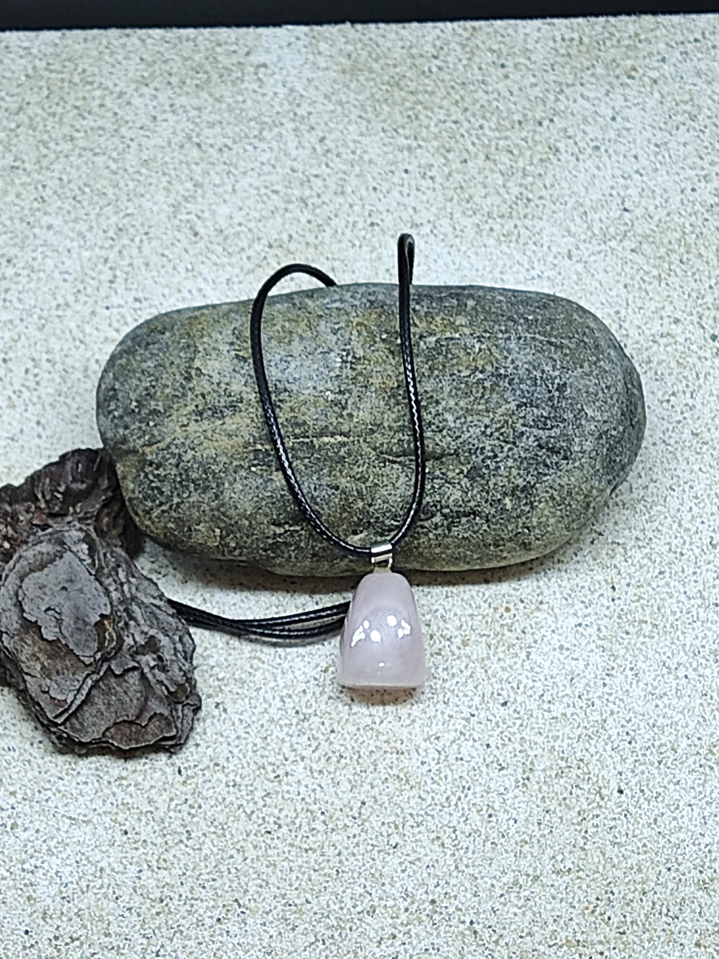 Colar com pendente de pedra rosa polida sobre pedra cinzenta