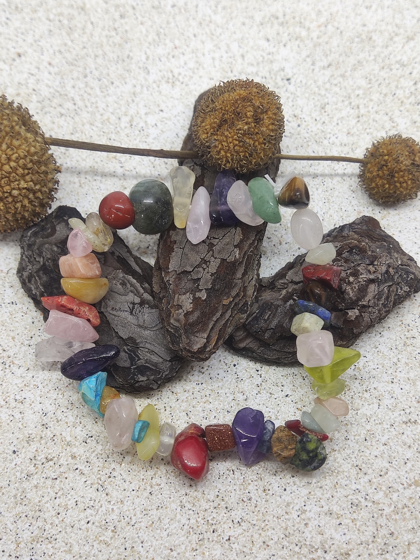 Pulseira de pedras semi-preciosas coloridas sobre pedaços de casca e flores secas