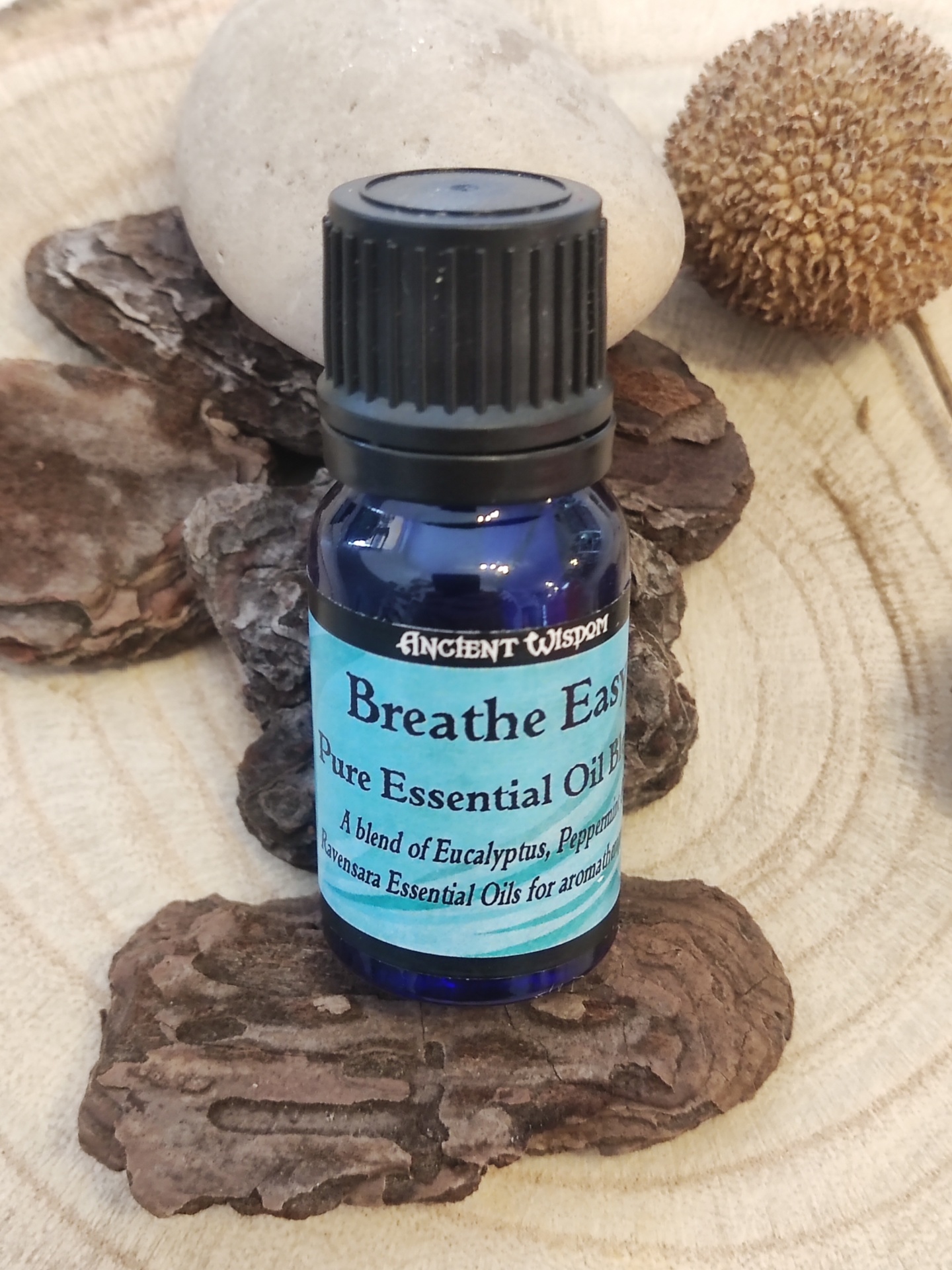 Frasco azul de óleo essencial sobre casca de árvore e pedras naturais