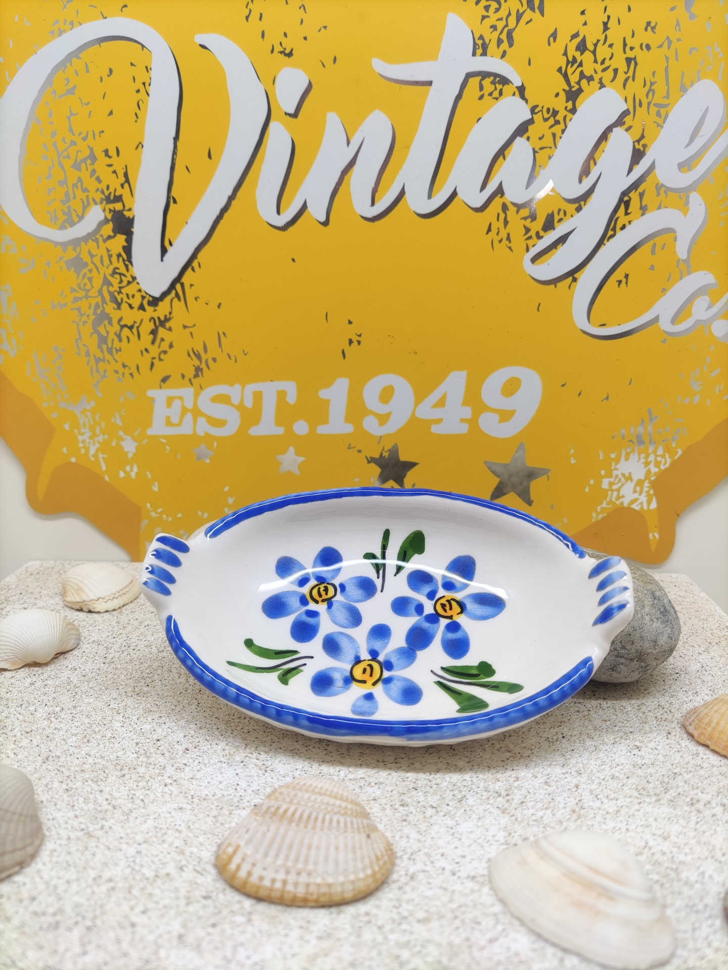 Prato decorativo de cerâmica com flores azuis e placa amarela Vintage ao fundo