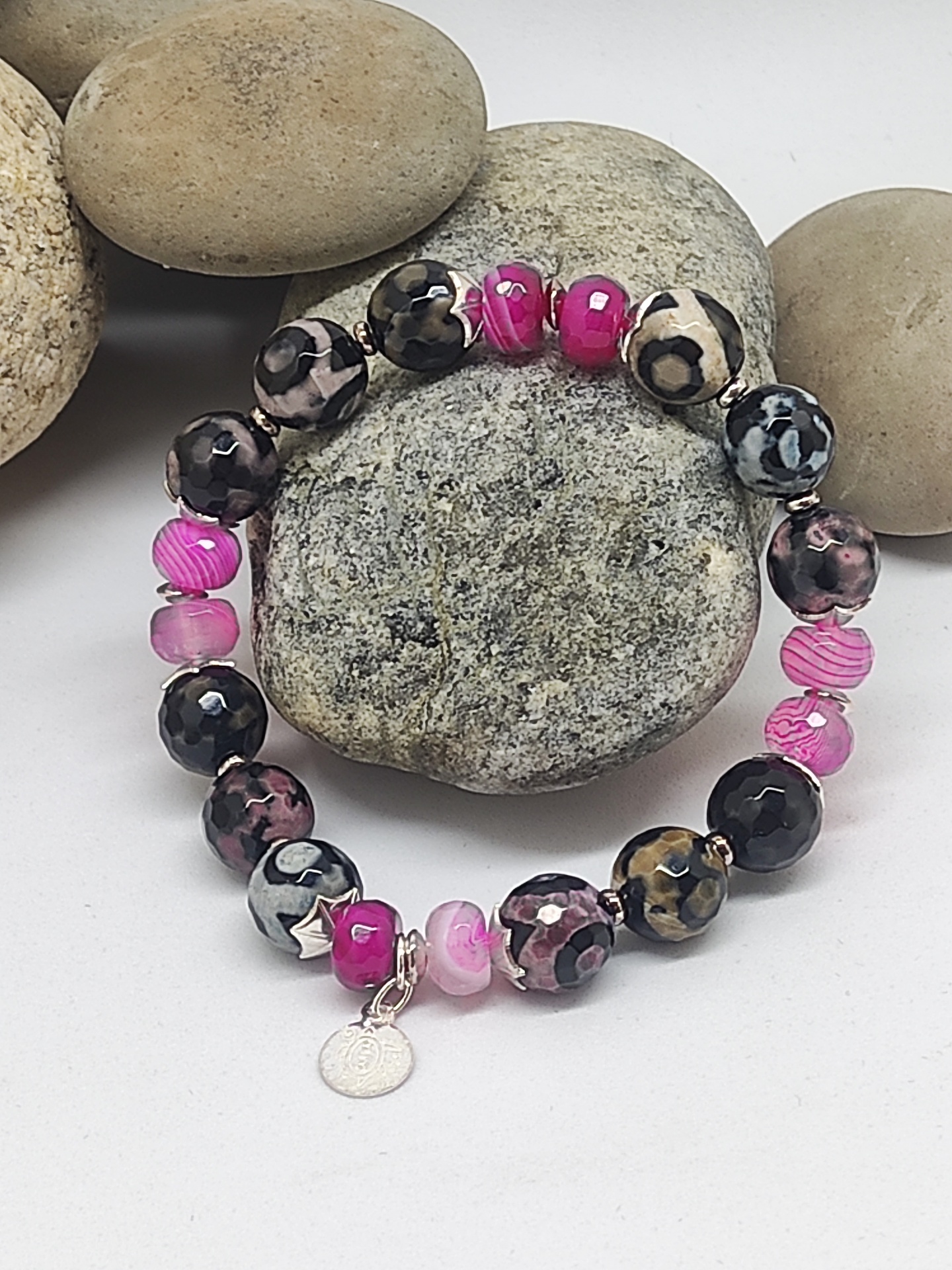 Pulseira colorida com contas redondas e pendente prateado sobre pedras