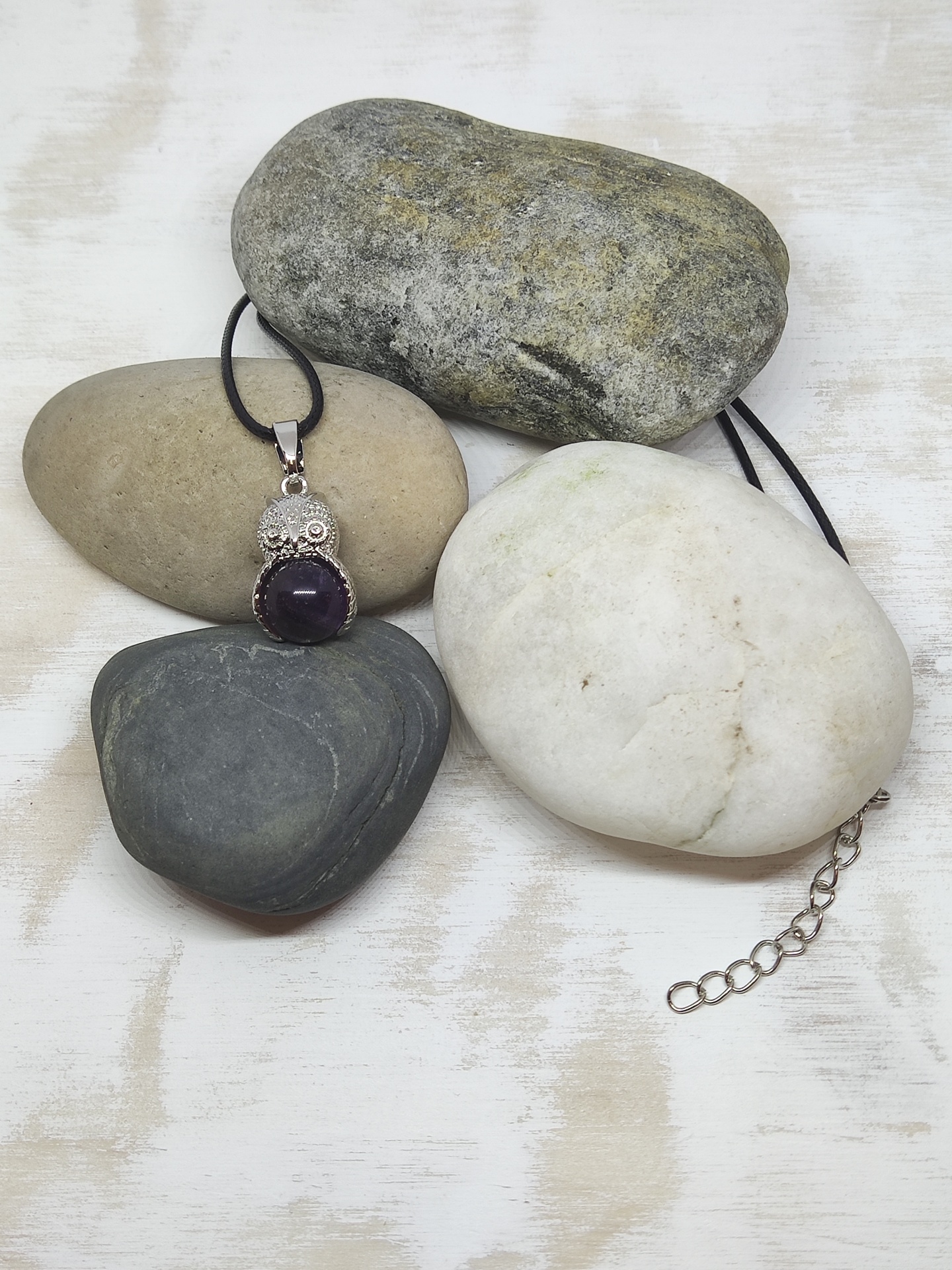 Colar com pendente de coruja em prata e pedra roxa sobre pedras lisas coloridas