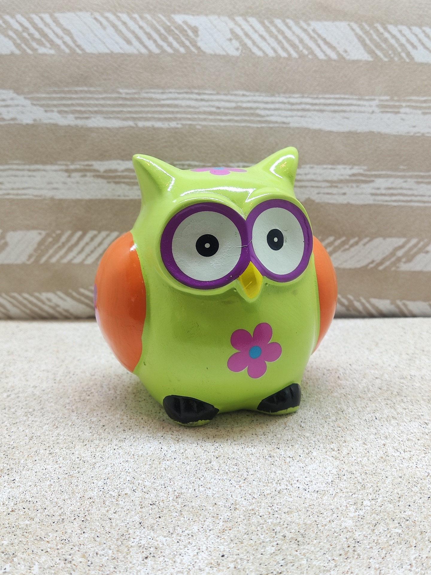 Figura decorativa de coruja verde com asas laranja e olhos grandes