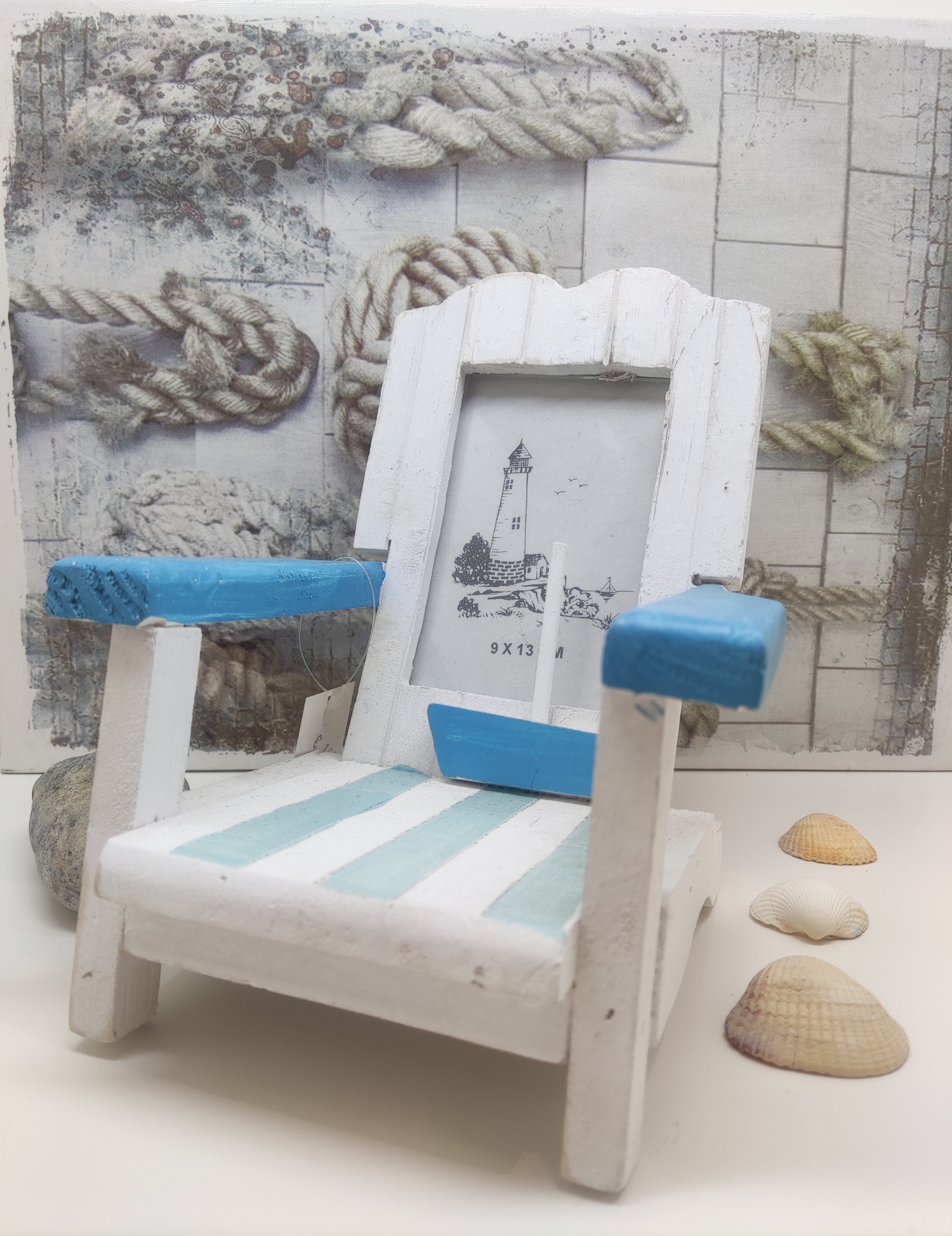 Cadeira decorativa madeira branca e azul com moldura para foto e conchas numa superfície branca.