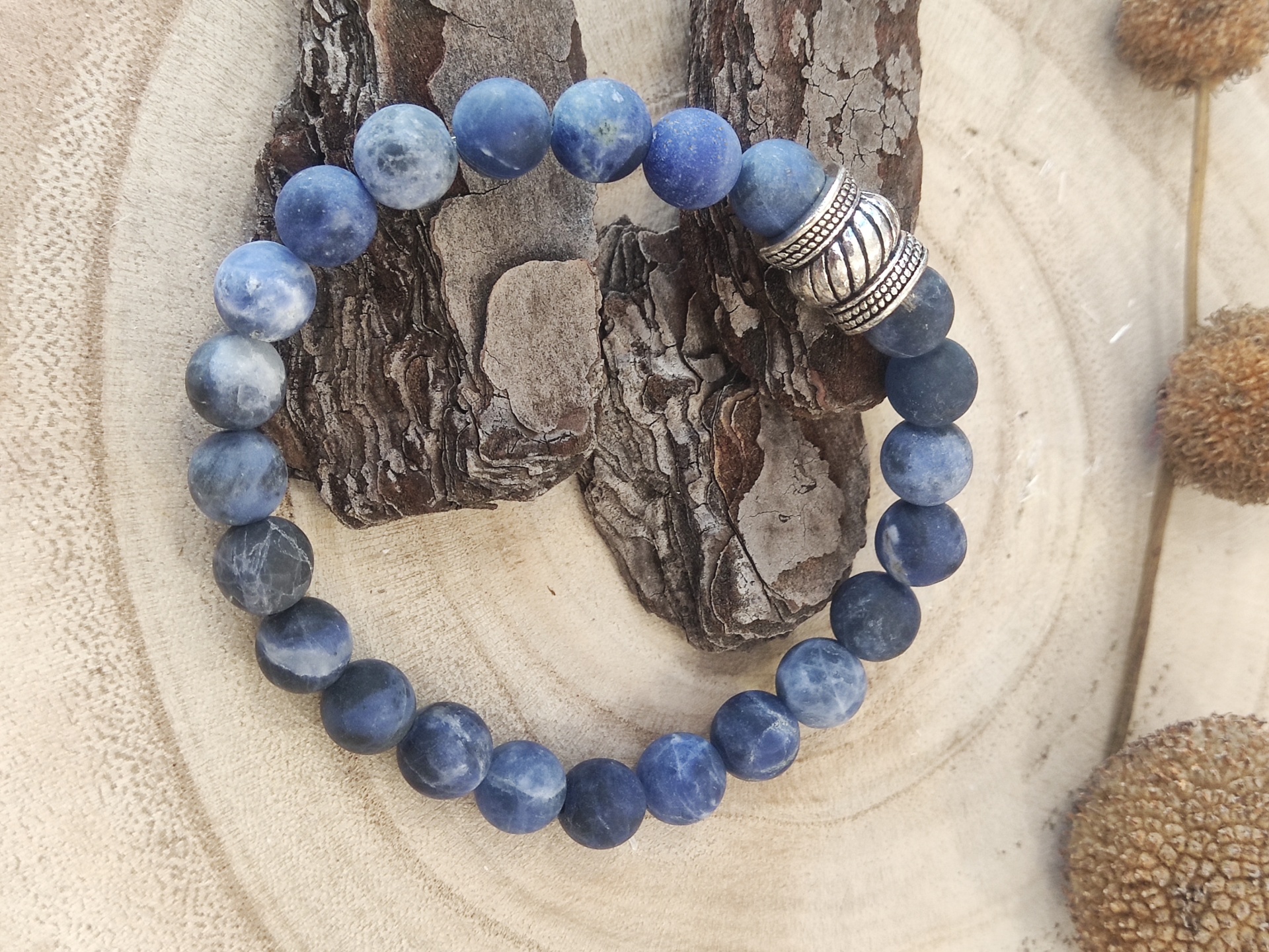 Pulseira de contas azuis com espaçador metálico sobre madeira clara