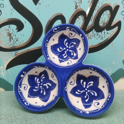 Conjunto de três pratos cerâmicos azuis e brancos com flores azuis, fundos azul e verde, palavra 'Soda' ao fundo