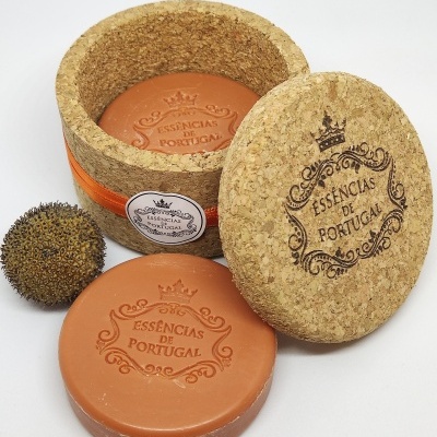 Sabonete laranja redondo com embalagem de cortiça e planta seca ao lado