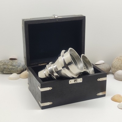 Caixa preta com copos de metal empilhados e conchas ao redor