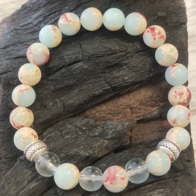 Pulseira de contas coloridas e transparentes com espaçadores metálicos prateados sobre fundo de madeira escura