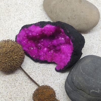 Geodo com cristais roxos, pedras naturais e objetos marrons sobre fundo branco