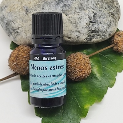 Frasco azul escuro de óleo essencial com rótulo azul claro sobre folhas e pedra