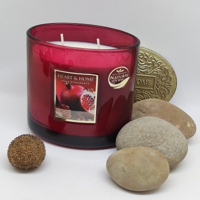 Vela aromática Heart & Home em copo de vidro vermelho rodeada de pedras