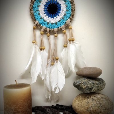 Filtro dos sonhos azul e branco com penas, vela, pedras e madeira