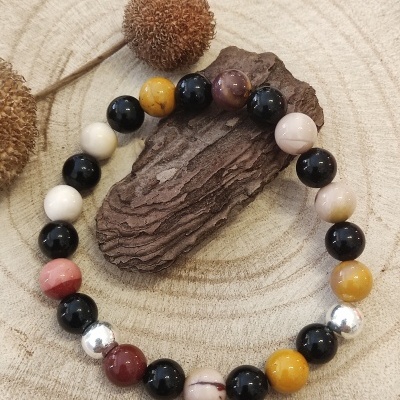 Pulseira colorida de contas sobre madeira clara e escura com decoração natural