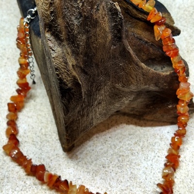 Colar de pedras laranja sobre base de madeira rugosa