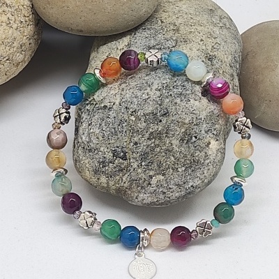 Pulseira elástica multicolorida com contas redondas e pendente OM sobre pedras.