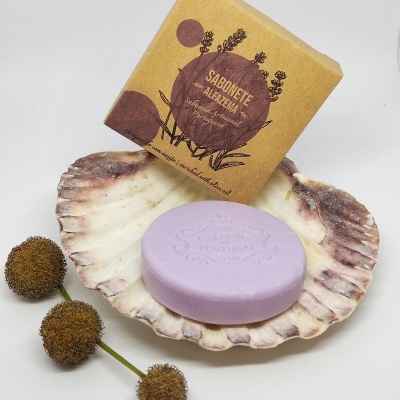 Sabonete lilás dentro de concha com embalagem castanha e flores secas ao lado.
