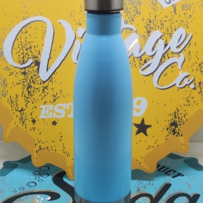 Garrafa térmica azul clara com tampa inox sobre fundo amarelo e azul com textos decorativos