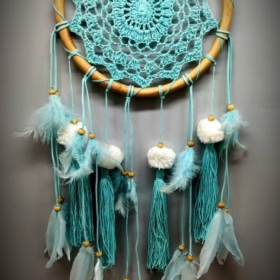 Filtro dos sonhos azul claro em aro de madeira com penas e franjas