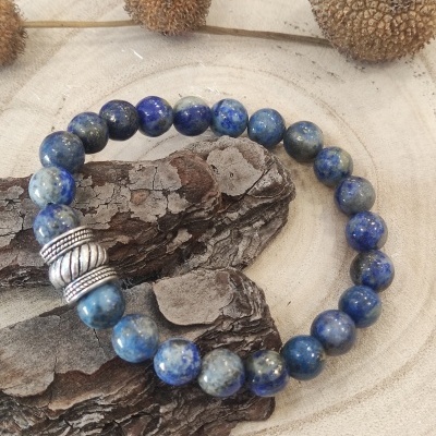 Pulseira de contas azuis e prata sobre casca de árvore com fundo claro