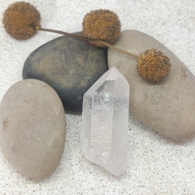 Três pedras lisas, galho seco com bolas castanhas e cristal transparente