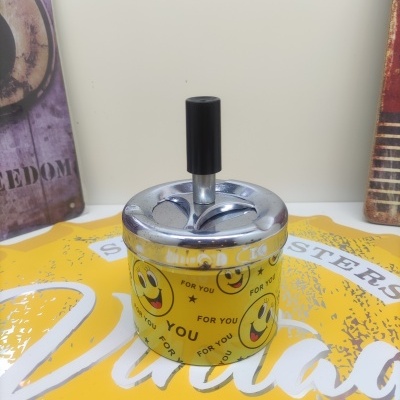 Cinzeiro amarelo com smileys e texto, tampa metálica com botão preto