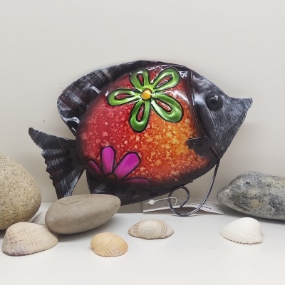 Peixe decorativo metálico colorido com padrão de flores entre pedras e conchas