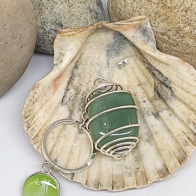 Chaveiro com pedra verde e medalha VIRGO sobre concha natural