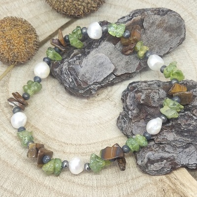 Pulseira artesanal com pedras verdes, olho de tigre, pérolas e contas pretas sobre madeira