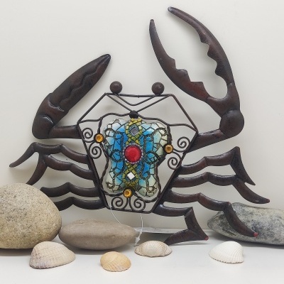 Escultura decorativa de caranguejo de metal com vidro colorido e pedras à frente