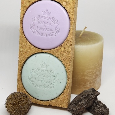 Dois sabonetes coloridos em base de cortiça com vela e elementos naturais ao lado