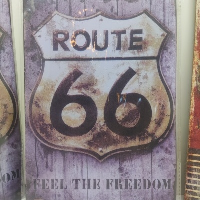 Placa metálica decorativa Route 66 com fundo roxo e texto FEEL THE FREEDOM