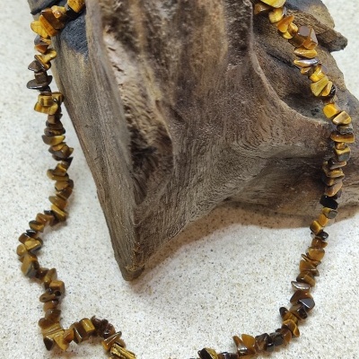 Colar de pedras naturais castanhas e amarelas sobre madeira
