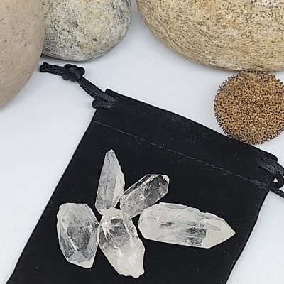 Cristais transparentes sobre bolsa de tecido preto com pedras ao redor