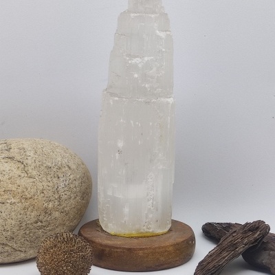 Cristal translúcido branco em base de madeira com pedras e madeira ao lado