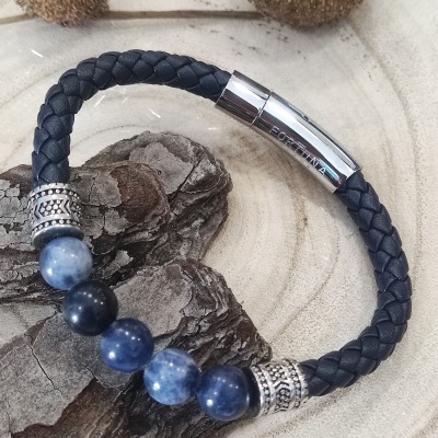 Pulseira preta com contas azuis e fecho prateado gravado PORTIMÃO sobre superfície de madeira