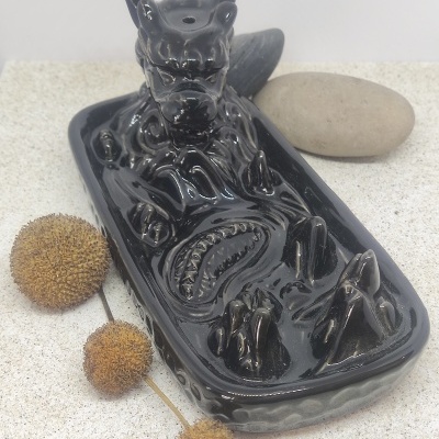 Escultura de dragão em cerâmica preta com pedra e frutos secos ao lado