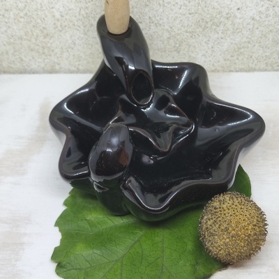 Incensário preto com cone de incenso sobre folha verde e bola marrom